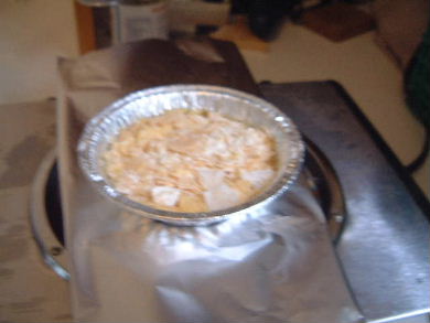 The three ingredients sitting in an aluminum plate sitting on a stove before melting.