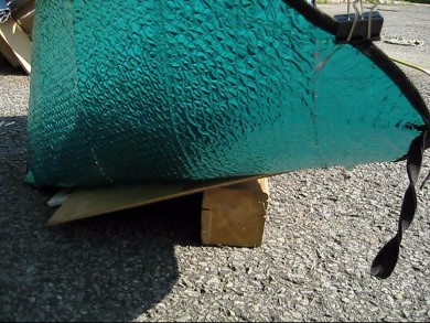 Car shade solar cooker propped up on a block of wood.