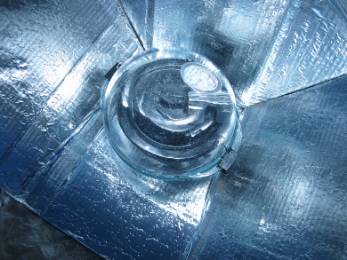 The black cooking pot inside a pyrex container on the 
      Modified CooKit solar cooker.