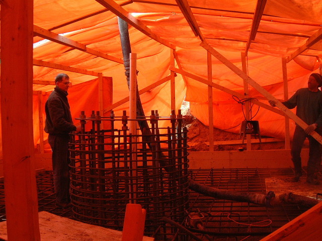 Concrete being delivered by a hose to inside the tarp building.