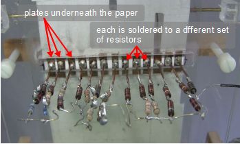 The plates and resistors underneath the paper of the 555 timer music player.