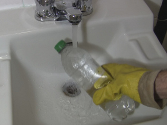 Running water over the bottle in a sink.