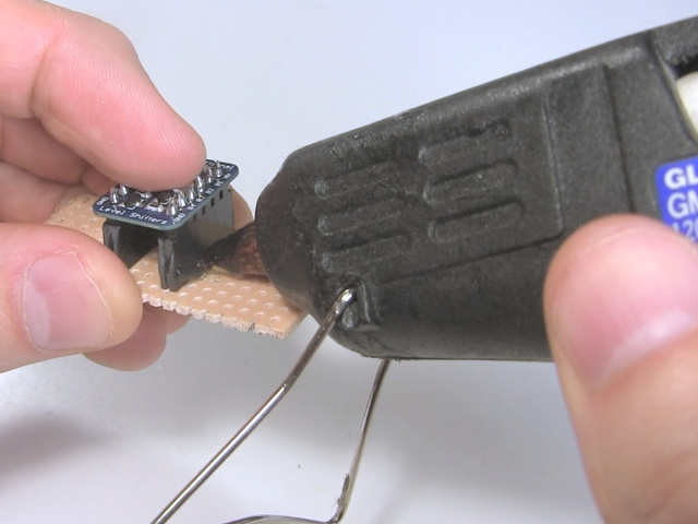 Hot gluing the female pin headers to the perfboard.